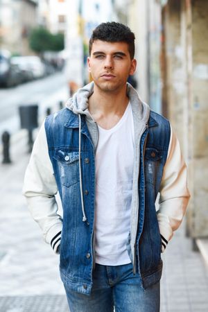 Serious man in jean jacket walking on street