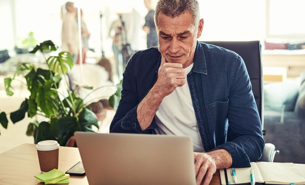 Thoughtful man working on his laptop in a bright office