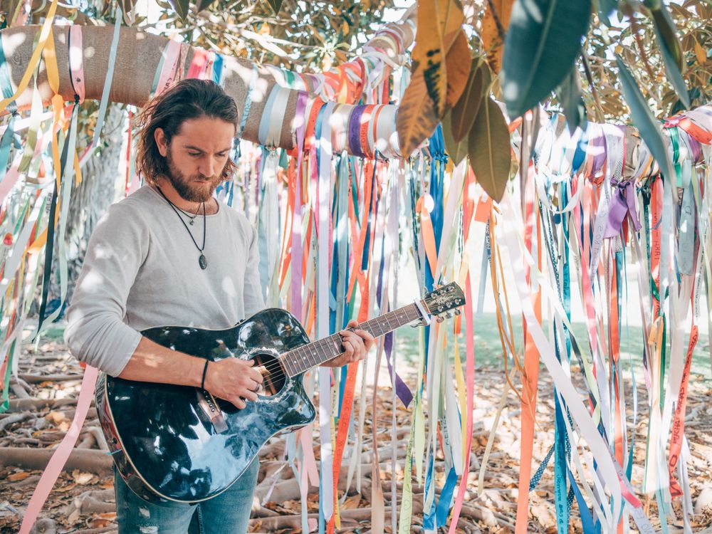 Man playing guitar under decorated tree