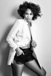 Monochrome side of female with curly hair in pajamas standing against wall in home