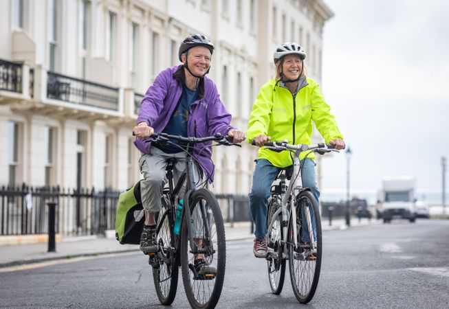 Two smiling older people riding bikes through town