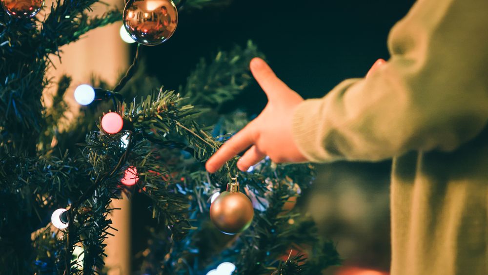 Boy decorating Christmas tree in evening