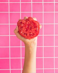 Hand holding half of red tomato and squeezing