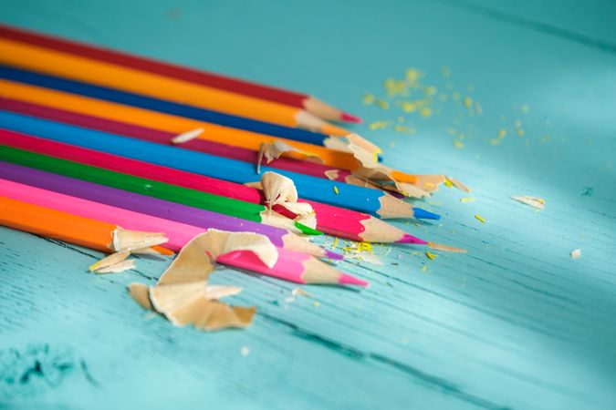 Coloured pencils arranged in a circle on a wooden background