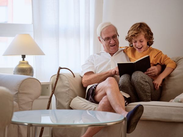 Smiling grandfather with grandson reading book