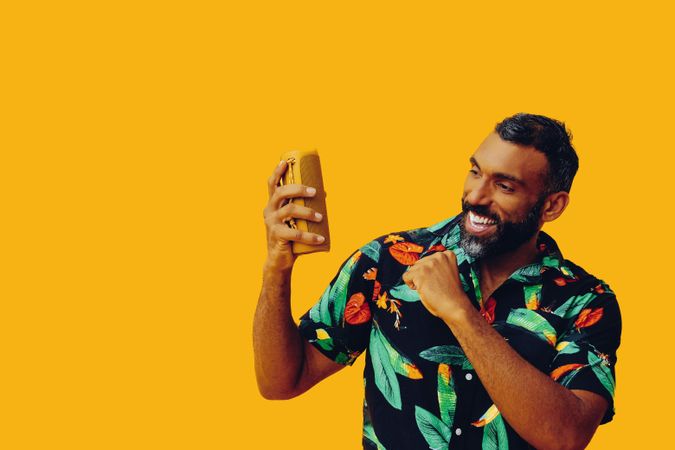 Black male in bold patterned shirt and small speaker in yellow room