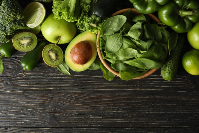 Green vegetables and fruits on wooden background
