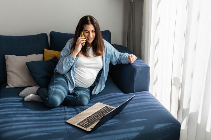 Pregnant woman talking on smartphone during remote work
