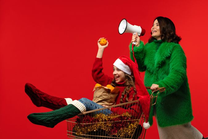 Woman announces with megaphone while girl lifts orange in cart