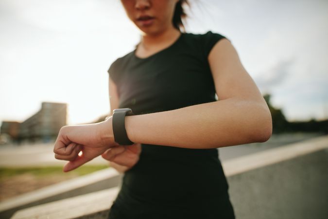 Close up shot of young woman runner using smartwatch outdoors