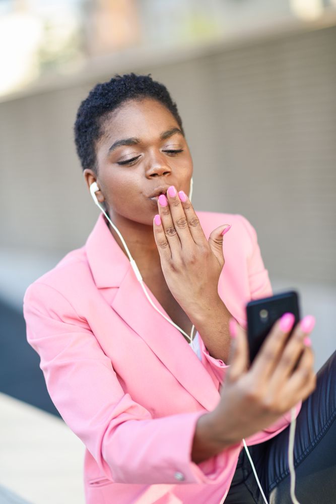 Female wearing suit with pink jacket greeting friend on video call