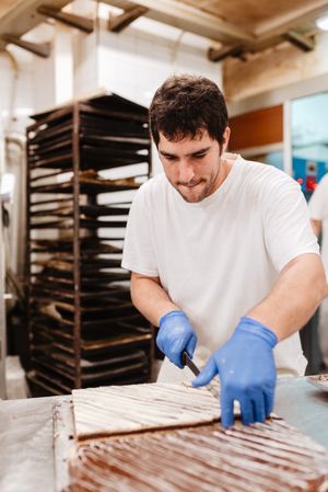 Anonymous cook cutting cake on table