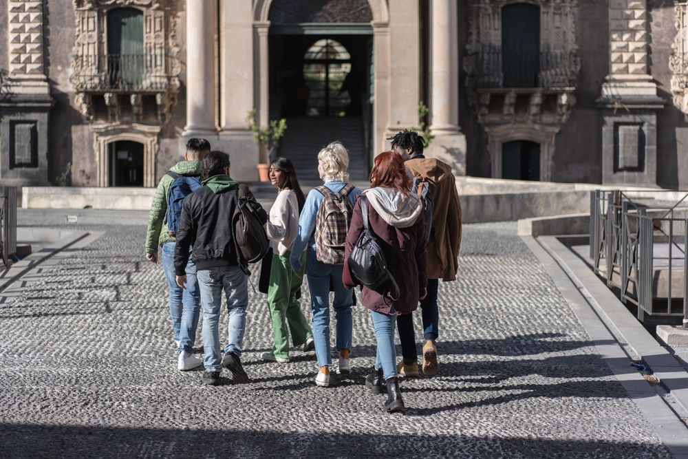 Multi-ethnic group of students walking through historic university campus