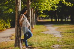 Pregnant female leaning on tree in park