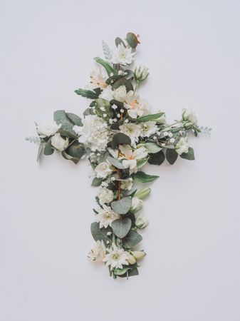 Easter layout with flowers and leaves in cross shape on light paper background