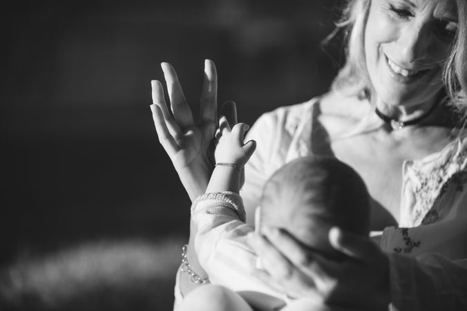 hands of a baby and his grandmother in black and white