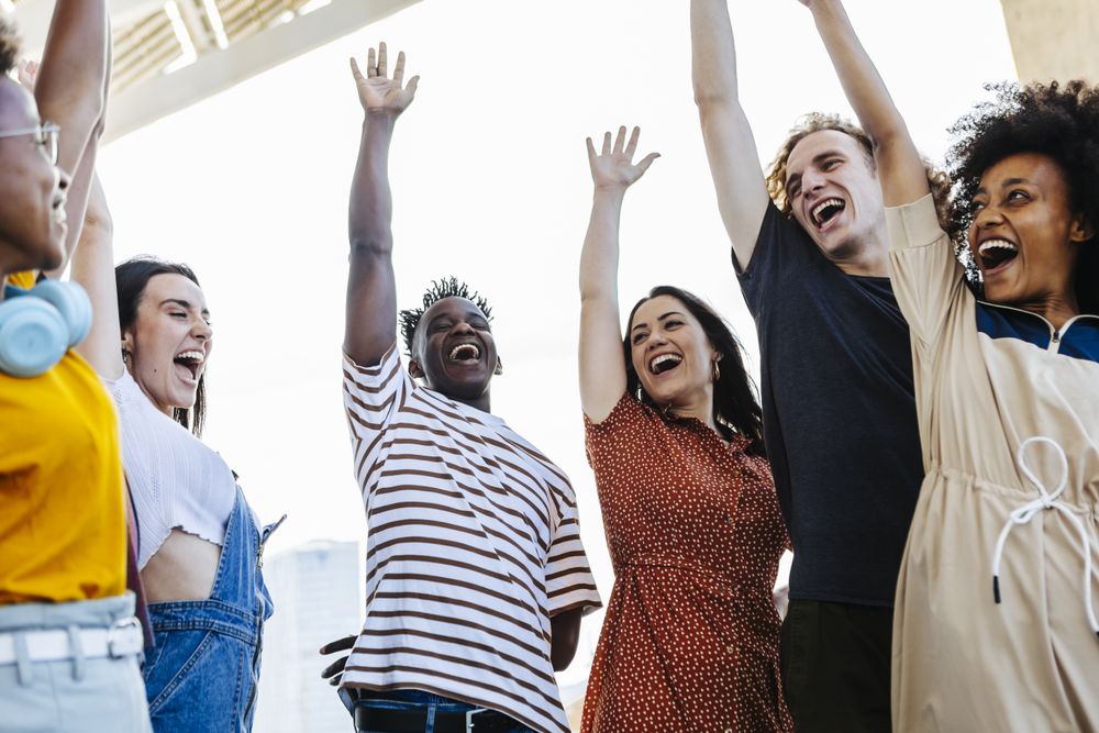 Group of young friends raising their hands in unity