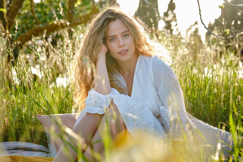 Dreamy young woman resting on grassy meadow in park