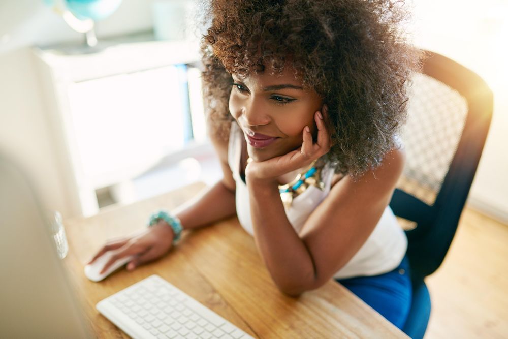 Looking down at curly haired female at her home office working at computer