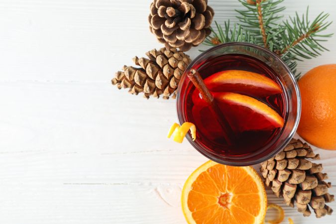 Glass of tasty mulled wine with orange on wooden background, space for text