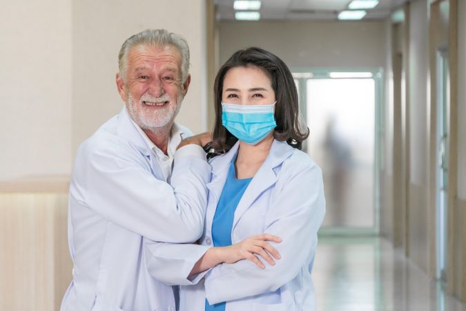 Male and female doctor smiling in hospital hallway