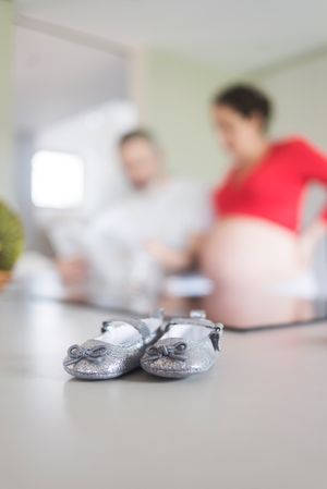 Baby shoes in foreground of pregnant woman with man