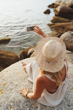 Contemporary woman with phone chilling on seashore