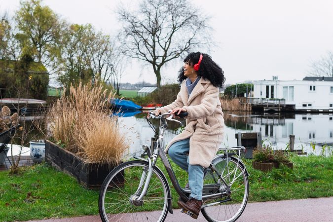 Excited Black woman in headphones riding bicycle