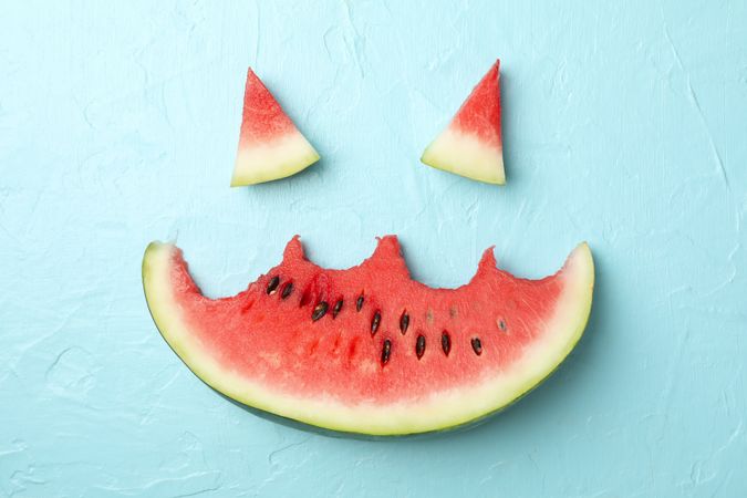 Smiley face made of watermelon on blue background, top view