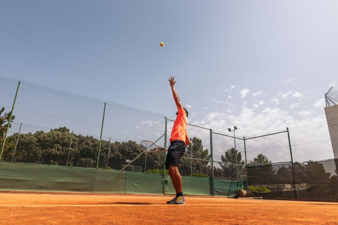 Man in sportswear playing tennis on a dirt tennis court