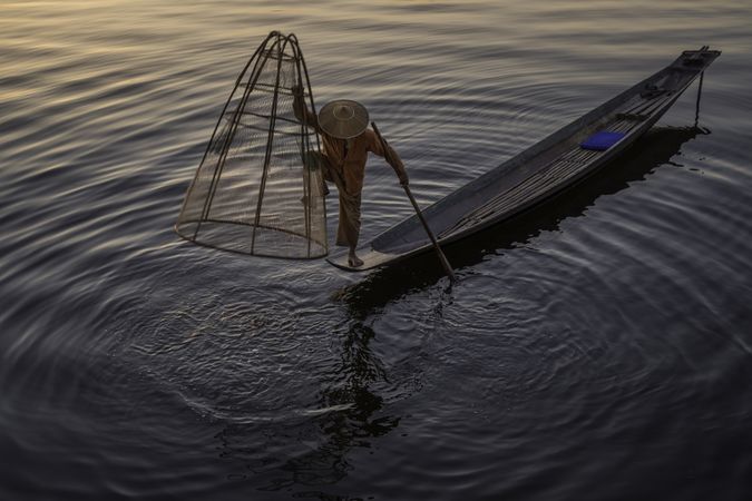 Fisherman standing on boat holding the fishing net in Myanmar