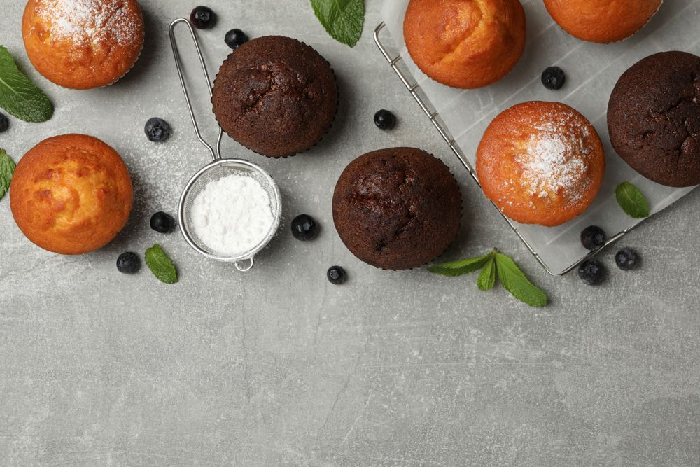 Composition with delicious muffins on gray background, top view