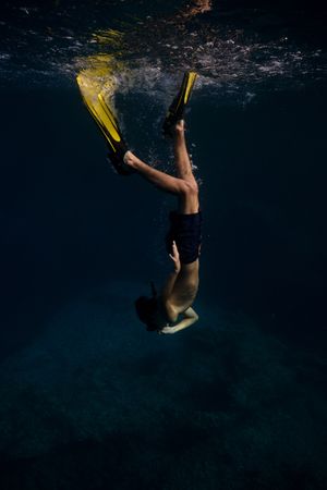 Unrecognizable man in flippers swimming underwater