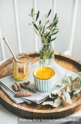 Warm turmeric latte in ceramic cup on wood tray with raw honey 5pVvxb