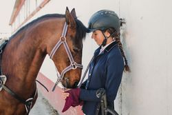 Woman in jockey outfit standing with horse