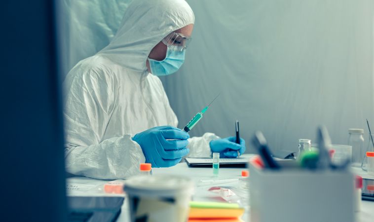 Scientist with protection suit investigating a vaccine in the laboratory