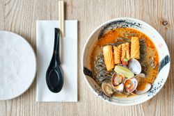 Soba soup with shellfish and crispy chicken skin near spoon