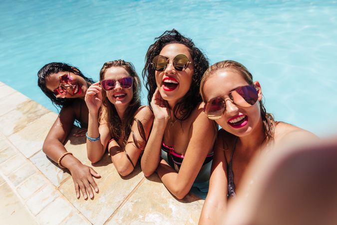 Cheerful women taking selfie photo in pool