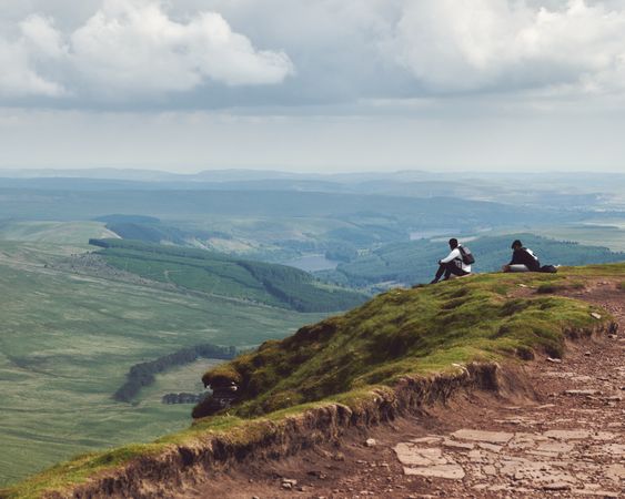 Two people sitting atop a mountain