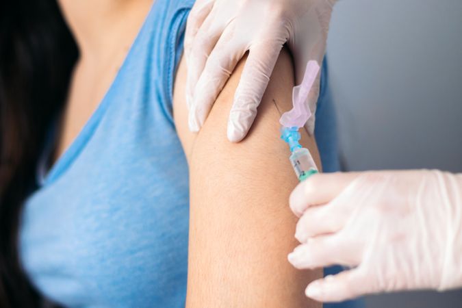 Vaccine in injection needle. Doctor working with patient's arm.