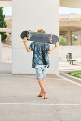 Boy with skateboard walking on street