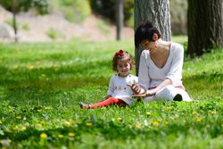 Woman sitting with girl in green sunny park