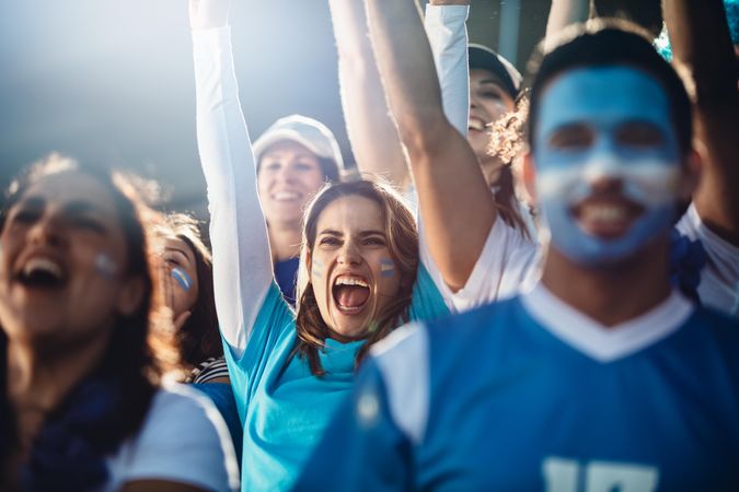 Argentinian woman with a group of cheering soccer fans in stadium