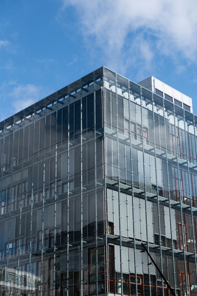 Glass facade of building against a blue sky with light clouds