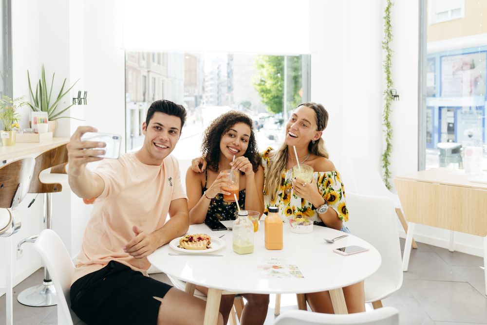 Man taking selfie of friends in cafe