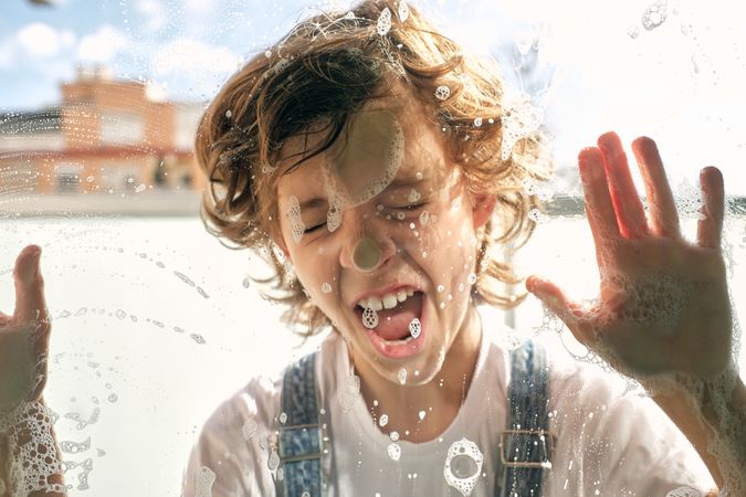 Happy child leaning on foamy window
