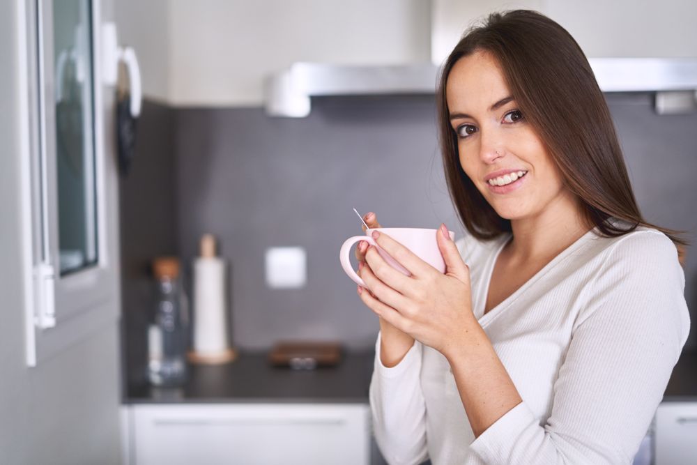 Woman drinking from cup in kitchen