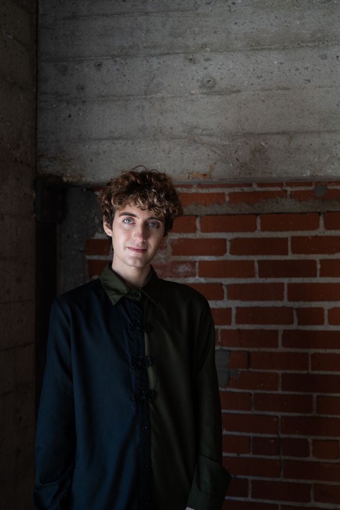 Portrait of nonbinary person against an exposed brick wall