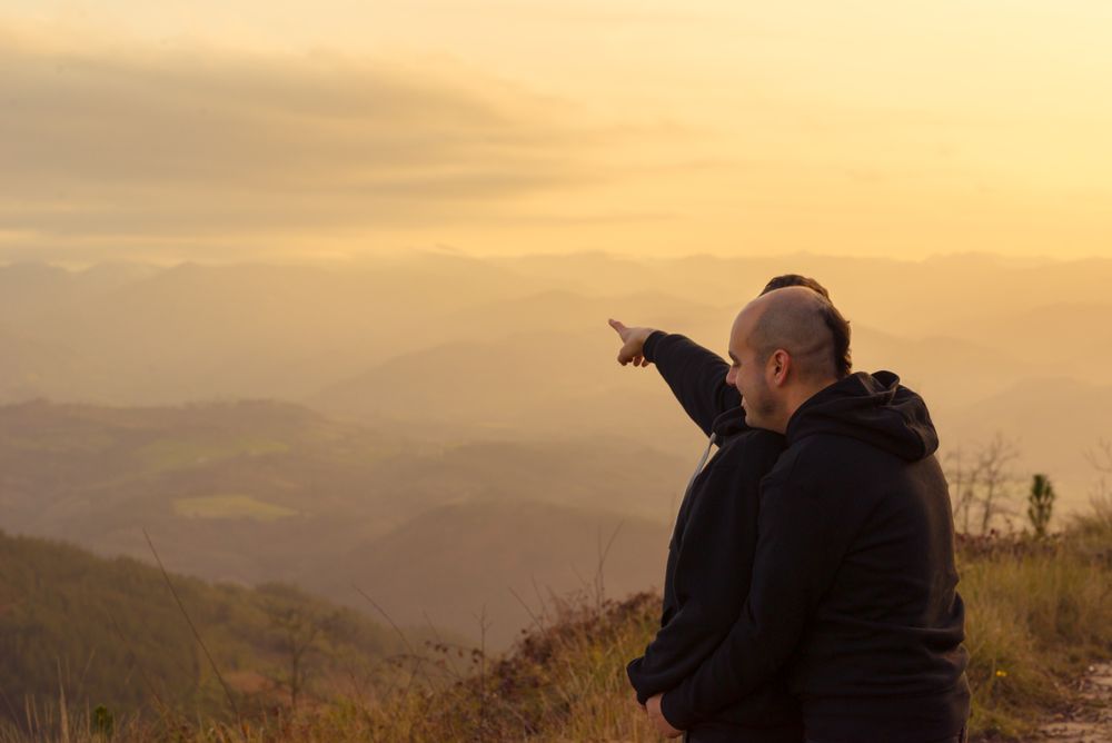 Men hugging on road on hill