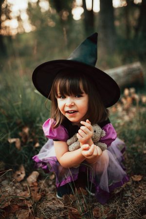 Girl with teddy bear in witch costume